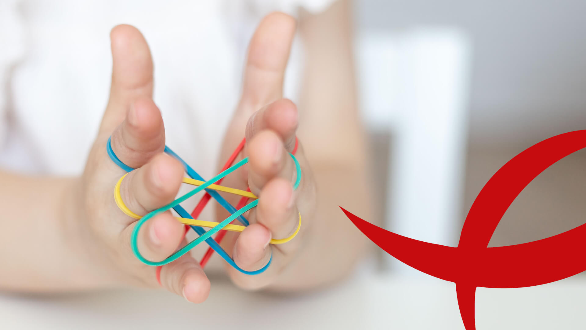 Ergotherapie I Praxis Kinderhände mit bunten Gummibändern in komplexem Fadenspiel.