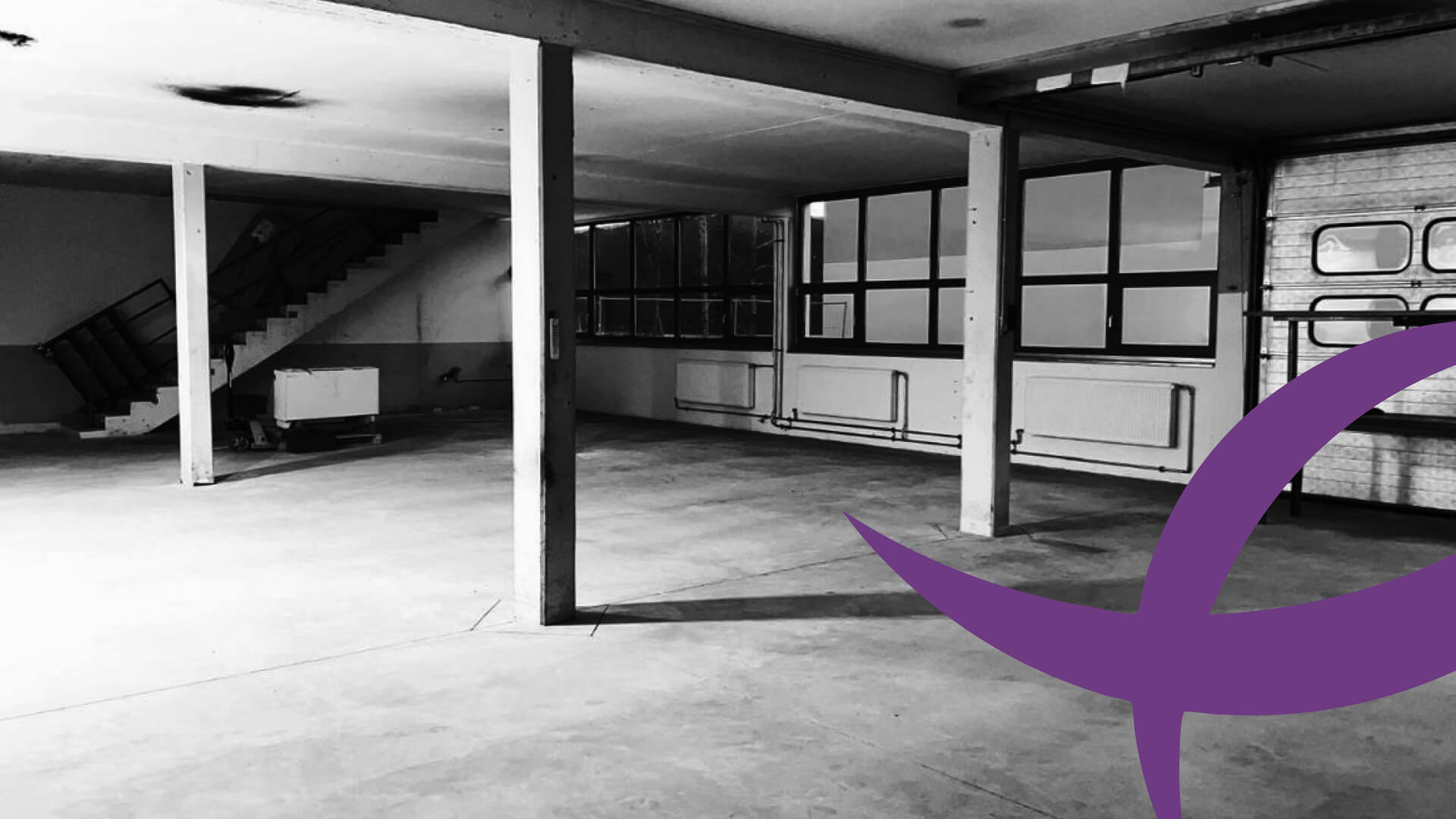 Wirk I Stätte Leere, industrielle Werkstattfläche mit Betonboden, Stahlträgern und großen Fenstern, teilweise mit einem lila grafischen Element im Vordergrund.